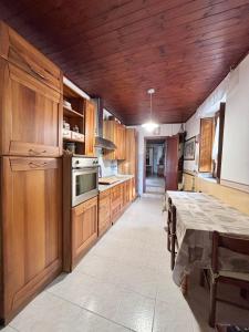 una cocina con armarios de madera y una mesa. en Appartamento in collina a 15 minuti dal mare, en Riparbella