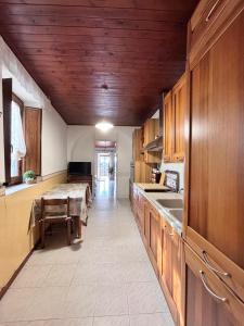 una cocina con armarios de madera y una mesa larga en Appartamento in collina a 15 minuti dal mare, en Riparbella