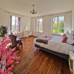 a bedroom with a bed and wooden floors and windows at Château des Aulnes 
