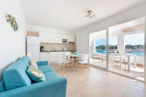 un salon avec un canapé bleu et une cuisine dans l'établissement Ferienwohnung für 4 Personen ca 60 qm in Portopetro, Mallorca Südostküste von Mallorca, à Portopetro
