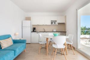 un salon avec un canapé bleu, une table et des chaises dans l'établissement Ferienwohnung für 4 Personen ca 60 qm in Portopetro, Mallorca Südostküste von Mallorca, à Portopetro
