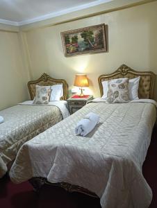 een slaapkamer met 2 bedden en een lamp op een tafel bij Krusty Hostel II in Huaraz