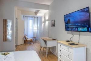 een woonkamer met een bureau en een tv aan de muur bij Studio entièrement rénové dans les rue piétonnes in Grenoble