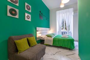 een groene slaapkamer met een bed en een bank bij Colori e Note in Napels