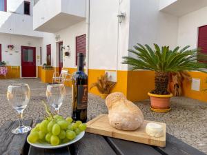 a table with a bottle of wine and a plate of grapes at Acolhedor espaço no centro da cidade in Évora