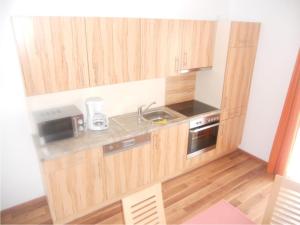 a small kitchen with wooden cabinets and a sink at Haus Annemarie in Wagrain