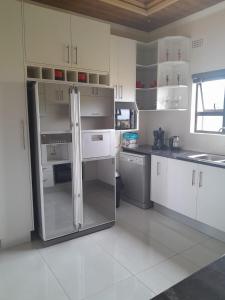 a kitchen with white cabinets and a stainless steel refrigerator at PHIL M AND PARTNERS ESTATES. in Manzini