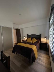a bedroom with a bed with a yellow blanket at Apartamento en Quetzaltenango in Quetzaltenango