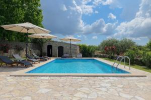 una piscina con 2 sombrillas en un patio en Ferienhaus mit Privatpool für 8 Personen ca 250 qm in Klarici, Istrien Binnenland von Istrien en Butkovići