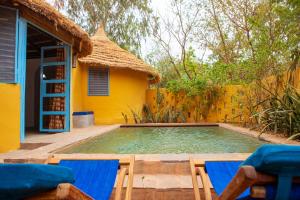 a swimming pool with two chairs and a house at Le Campement in Bamako
