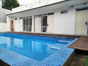 a swimming pool with blue tiles in front of a house at Jardine Villa 002 in Babakan Madang