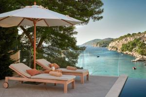 赫瓦爾的住宿－Beautiful Villa Crystalsea 2 with a pool in Hvar，两把躺椅和一把雨伞,紧靠水体