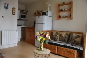 uma sala de estar com um sofá e um vaso de flores em Appartement 1 chambre, avec loggia et vue sur le Port Olona em La Chaume