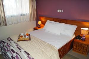 a bedroom with a bed with a tray of food on it at Hôtel Sol Béni in Abidjan