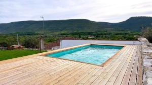 a swimming pool on a wooden deck with mountains in the background at Casa de Alcaria in Alcaria