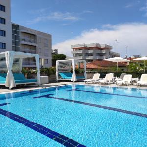 a large swimming pool with chairs and a building at Hotel Atlantico in Lido di Jesolo