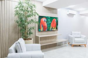 a living room with a painting of parrots on the wall at Hotel Place Jardin in Garanhuns