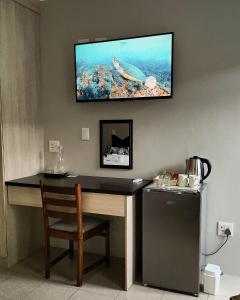 Pokój z biurkiem i telewizorem na ścianie w obiekcie Waterlily Cove Guesthouse w mieście Pretoria
