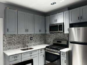 uma cozinha com armários brancos, um fogão e micro-ondas em 3 bedrooms in Modern Brooklyn home, Close to J train em Brooklyn