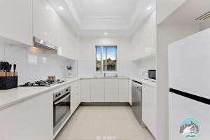 ウェントワースビルにあるAircabin - Wentworthville - 2 Beds Apt Free Parkの白いキャビネットと窓付きの白いキッチン