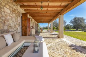 an outdoor living room with a couch and a stone wall at Finca Sa Torreta in Santa Margalida