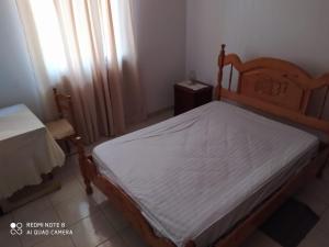 a bedroom with a wooden bed with a white mattress at Chez Lopes in Praia