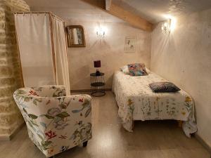 a small bedroom with a bed and a chair at La Maison de Margot in Xaintray