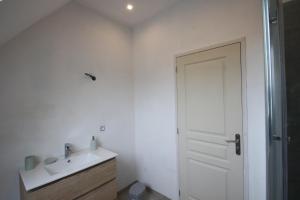 een witte badkamer met een wastafel en een deur bij gîte du germinais in Saint-Germain-du-Pert