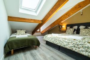 - une chambre mansardée avec 2 lits et une fenêtre dans l'établissement Mon Appart'hôtel - Gare de Limoges - Duplex 2 Chambres - Parking en supp, à Limoges