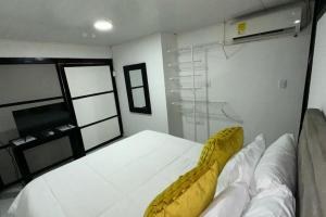 a bedroom with a white bed with a yellow couch at Rio Aparta-Hotel 2 in Leticia