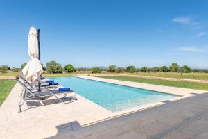 une piscine avec deux chaises et un parasol dans l'établissement Ferienhaus mit Privatpool für 8 Personen ca 430 qm in Felanitx, Mallorca Südostküste von Mallorca, à Felanitx