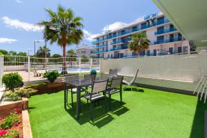 un patio con mesa y sillas en el césped en UHC Mar Augusta Family Complex en Cambrils