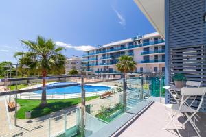 Cet appartement dispose d'un balcon avec une piscine et des palmiers. dans l'établissement UHC Mar Augusta Family Complex, à Cambrils
