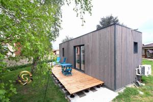 une petite maison grise avec une terrasse en bois dans l'établissement Tiny House Saint Cyr sur Menthon, à Saint-Cyr-sur-Menthon