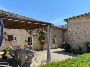 a patio with a table and chairs under a pergola at La Maison de Margot in Xaintray