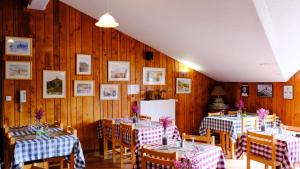 una sala da pranzo con tavoli, sedie e pareti in legno di AU CHAT BLEU a Saint-Laurent-les-Bains