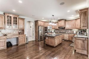 a large kitchen with wooden cabinets and wooden floors at Beautiful relaxing private villa next to a pond smart home and Traeger Grill in Overland Park