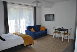 ein Schlafzimmer mit einem Bett, einem blauen Stuhl und einem Tisch in der Unterkunft Apart4You Apartamenty Nowy Targ in Nowy Targ