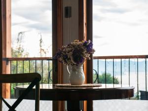 un jarrón de flores sentado en una mesa en un balcón en Cabaña rustica con vista al mar en Puerto Montt