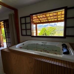 eine große Badewanne in einem Zimmer mit Fenster in der Unterkunft Pousada Vista Pedra Azul in Pedra Azul