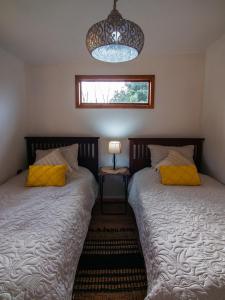 sypialnia z 2 łóżkami i żyrandolem w obiekcie Cabaña rustica con vista al mar w mieście Puerto Montt