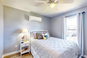a bedroom with a bed with a ceiling fan and a window at Bogue Banks Beauty - Unit A in Atlantic Beach