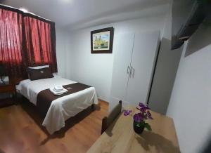 a bedroom with a bed and a table with flowers at Hotel Los Reyes in Cajamarca