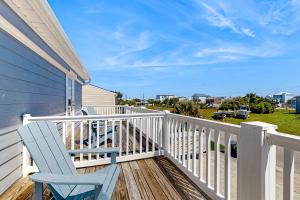 a blue rocking chair on a porch with a view of the ocean at Bogue Banks Beauty - Unit A in Atlantic Beach