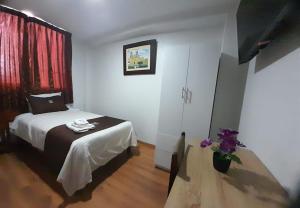 um quarto com uma cama e um vaso de flores em Hotel Los Reyes em Cajamarca