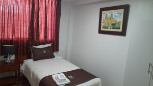 um pequeno quarto com uma cama e uma fotografia na parede em Hotel Los Reyes em Cajamarca
