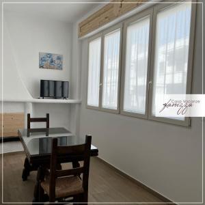 een eetkamer met een tafel, stoelen en ramen bij Fanizza apartment 16 in Alberobello