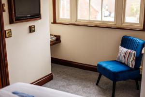 Habitación con silla azul y TV. en The Old Townhouse - Room 3, en Poole