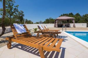 a group of deck chairs sitting next to a swimming pool at Villa La Plazza in Dugopolje
