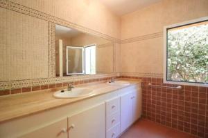 a bathroom with two sinks and a mirror and a window at Villa Diana in Cala'n Porter +19 photos